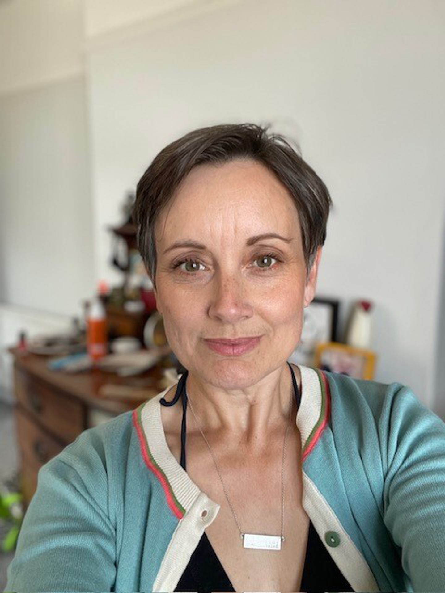 A woman with short dark hair smiles at the camera